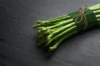Gebündelter grüner Spargel mit Bindfaden auf dunklem Untergrund